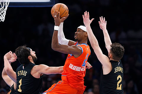 NBA 2024-25: Thunder guard Shai Gilgeous-Alexander looks to pass the ball away from Cleveland Cavaliers guards