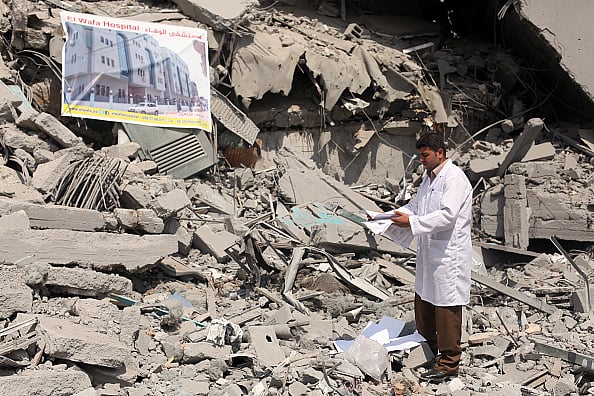 Palestinian doctor inspects devastation the headquarters of El-Wafa rehabilitation hospital - Getty Images