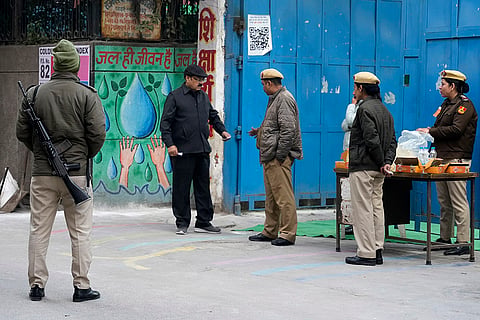 Delhi Elections 2025 Voting: A police officer checks the identity card of a voter