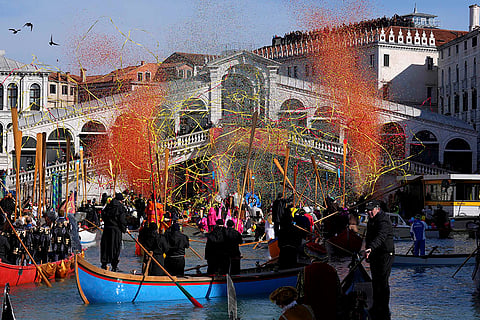 2025 Venice Carnival: Boats sail as confetti explodes in the air under the Rialto bridge