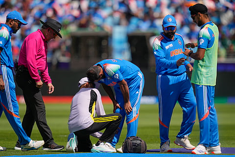 India's Mohammed Shami, centre, is attended by the team physio during the ICC Champions Trophy cricket match between India and Pakistan at Dubai International Cricket Stadium, United Arab Emirates, Sunday, Feb. 23, 2025.