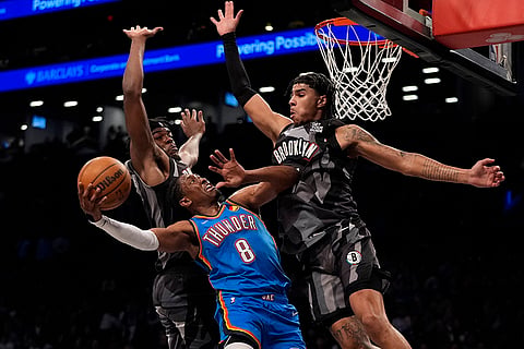 NBA 2024-25: Thunder's Jalen Williams, center, shoots over Brooklyn Nets' plalyers