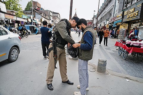 A policeman checks a pedestrian’s bag near the Clock Tower in Srinagar on April 22