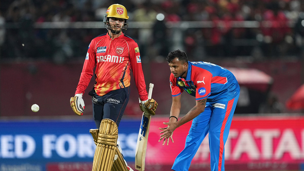 AP Photo/Ashwini Bhatia : Delhi Capitals' T Natarajan, right, collects the ball as Punjab Kings' Priyansh Arya walks past during the Indian Premier League cricket match in Dharamshala.
