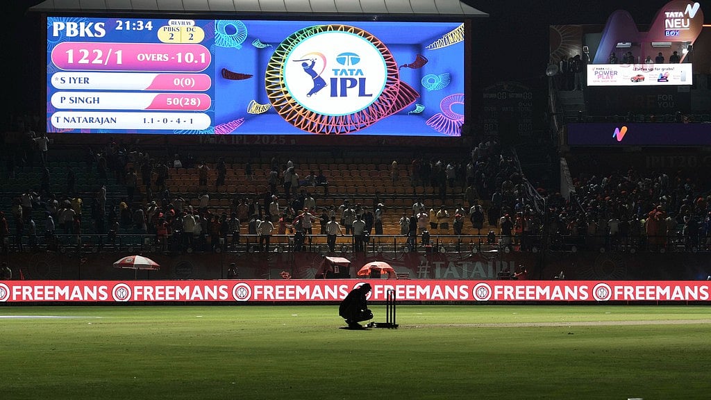 A worker removes the equipment placed next to the stumps after the authorities asked to evacuate the stadium during the Indian Premier League match between Punjab Kings and Delhi Capitals in Dharamsala. - AP