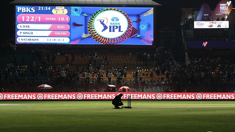 A worker removes the equipment placed next to the stumps after the authorities asked to evacuate the stadium during the Indian Premier League match between Punjab Kings and Delhi Capitals in Dharamsala. - AP