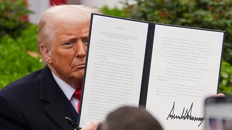 President Donald Trump holds a signed executive order to announce new tariffs in the White House.