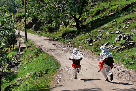Safety First: Two school 
girls rush back home. A security personnel is seen guarding the road