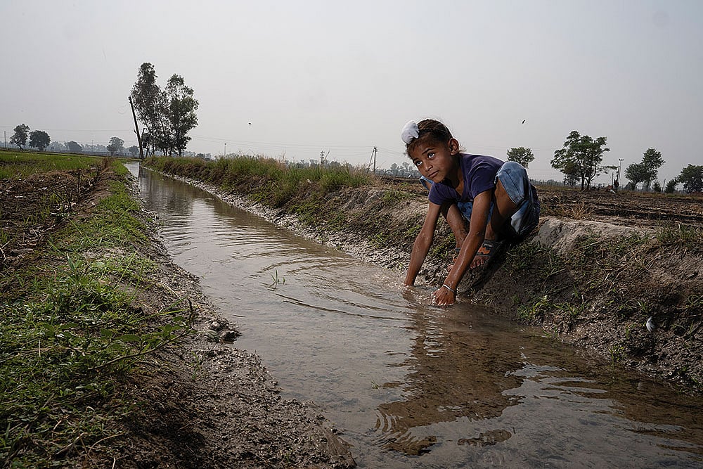  A young boy plays in an irrigation canal at Daoke