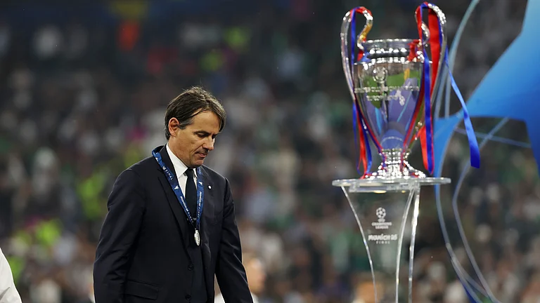 A forlorn Simone Inzaghi walks past the Champions League trophy - null