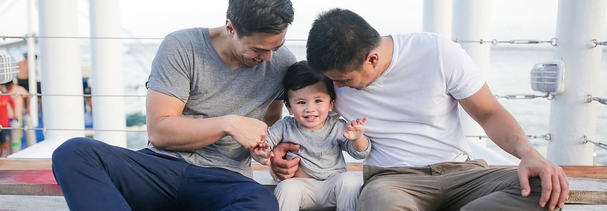 Two Gay Fathers And A Child Sitting Together