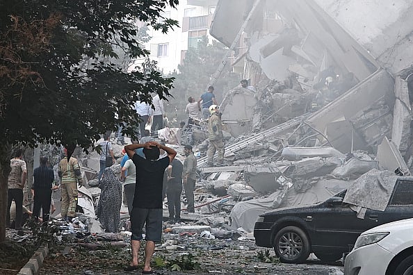 Majid Saeedi/Getty Images : People look over damage to buildings following Israeli airstrikes on June 13 in Tehran