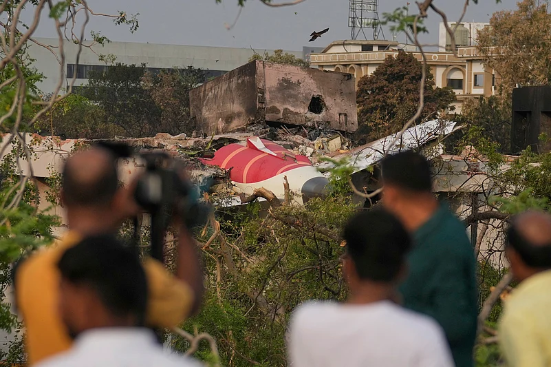Onlookers watch wreckage from Thursdays Air India plane crash lying atop a building in Ahmedabad