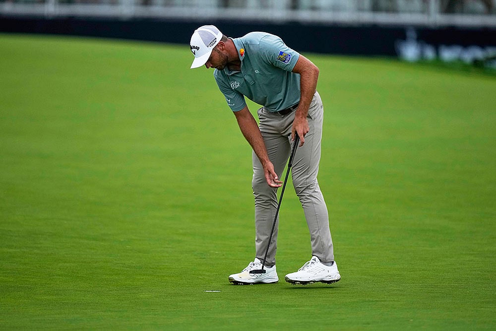 Sam Burns looks in the cup after making double bogey on the 15th hole