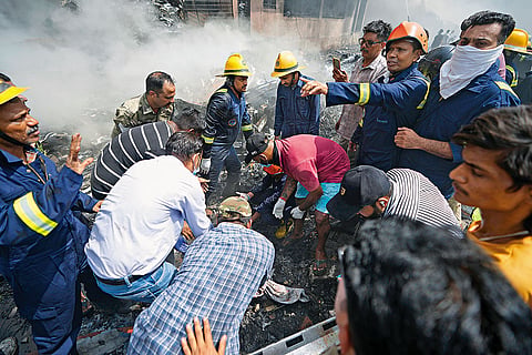 Firefighters and volunteers look for charred bodies beneath the wreakage of the plane