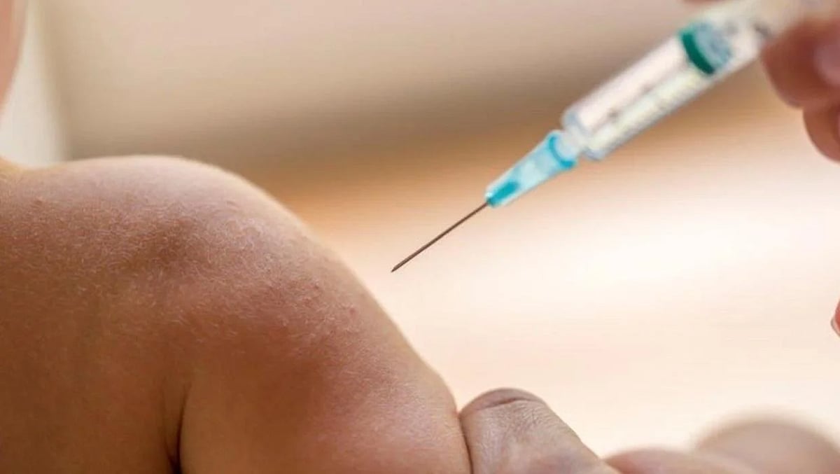 A close-up of a syringe being injected into a childs arm