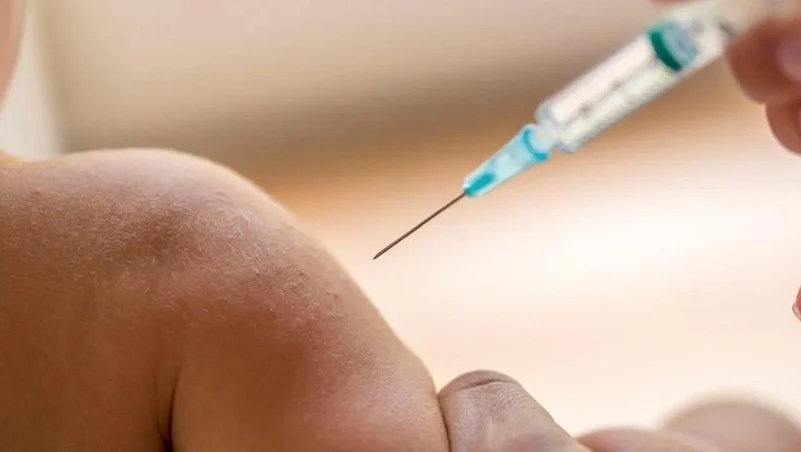 A close-up of a syringe being injected into a childs arm