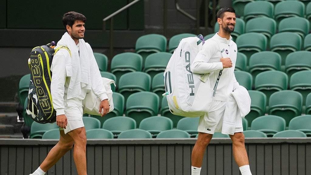 AP : Novak Djokovic, right, and Carlos Alcaraz, left, arrive for a practice session on centre court at the All England Lawn Tennis and Croquet Club ahead of the Wimbledon Championships in London.