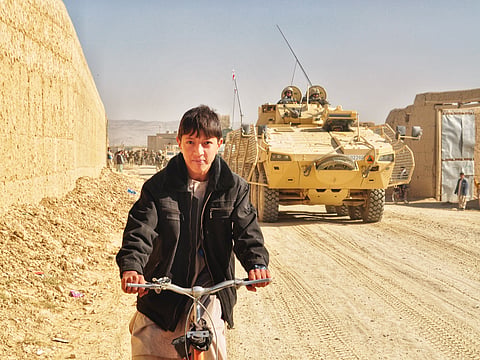 A boy riding a bicycle amidst Afghan War