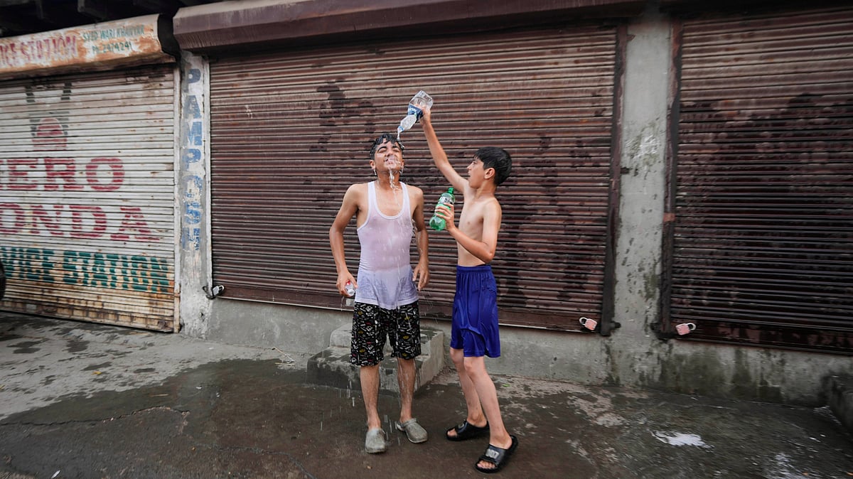 A boy pours water on his friend as they cool off on a hot summer day in Srinagar, Kashmir, Tuesday, June 24, 2025. - Mukhtar Khan - AP    