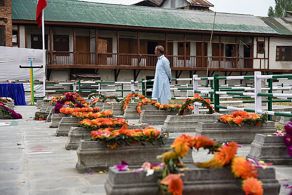 gettyimages | : A Kashmiri man pays tribute next to graves of 22 civilians at Martyr's graveyard in Srinagar. July 13 is observed as Martyrs Day in Jammu and Kashmir to remember those 22 civilians killed in the firing outside the Srinagar Central Jail by forces of the Dogra Maharaja in 1931 |