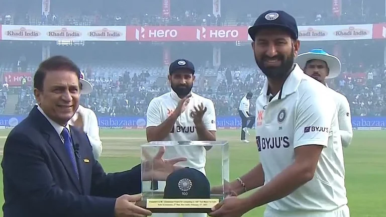 Sunil Gavaskar presenting a special cap to Pujara during the latter's 100th Test match. - BCCI