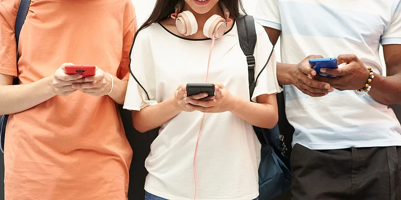 Three teenagers using mobile phones