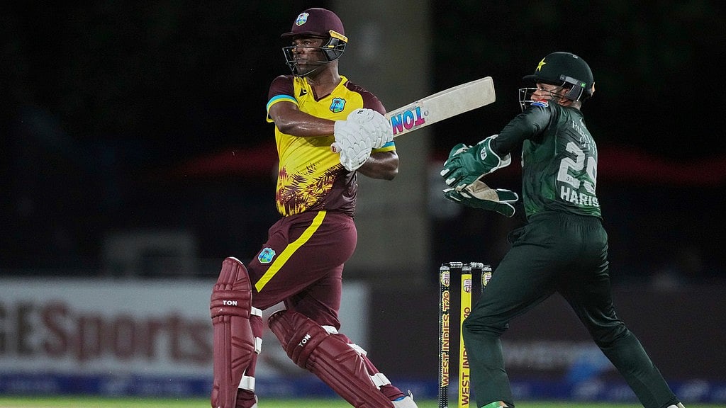 AP : Johnson Charles, left, follows the ball after playing a shot for boundary as Pakistan's Mohammad Haris watches during the first Twenty20 cricket match between West Indies and Pakistan.