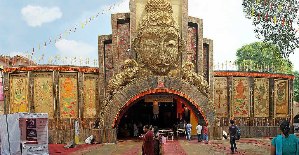 The ornate entrance of a Durga Puja pandal with a large sculpted face.