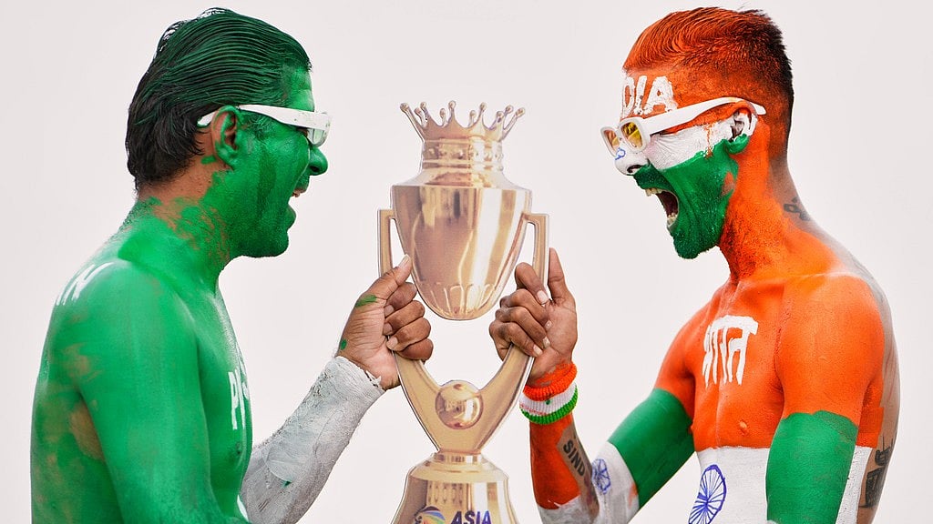 AP : Indian cricket fans, with their bodies painted in the colours of Indian and Pakistan flags, pose for the media with a cutout image of the Asia Cup trophy in Ahmedabad.