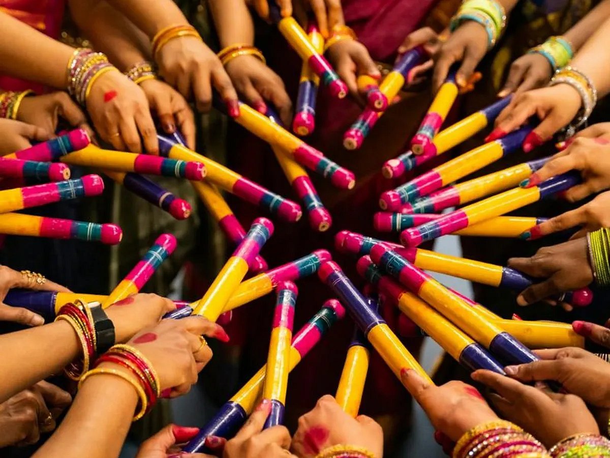 Hands holding colorful dandiya sticks during Navratri celebration.