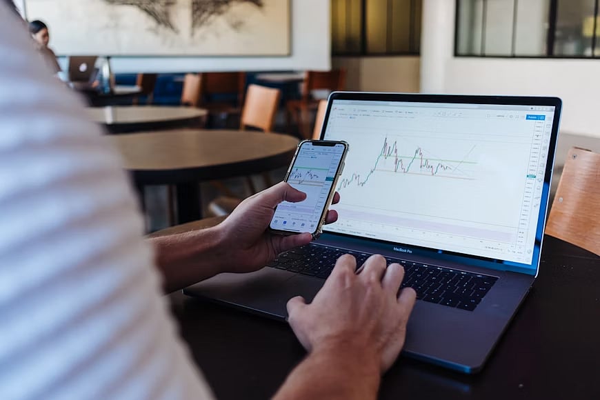A Person using a laptop and smartphone simultaneously.