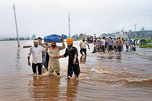 Photo: PTI : Water, Water Everywhere: Locals assist in moving flood affected people to a safer place as floodwater enters villages in Ajnala, near Amritsar