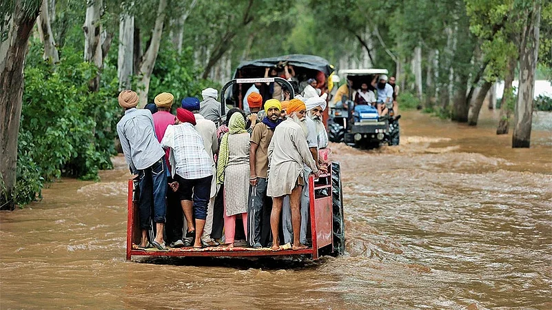 Villagers commute on tractors through the flood waters at Ghonewala village