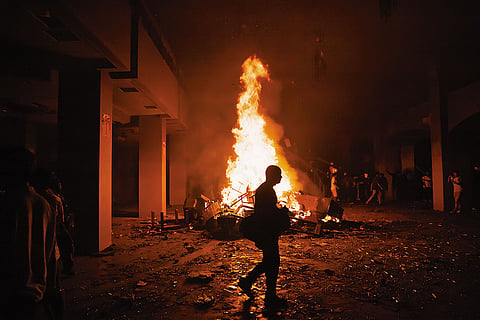 Fiery Revolt: A protester walks in front of a fire ignited by arsonists in the lobby of the Parliament building in Kathmandu on September 9, 2025