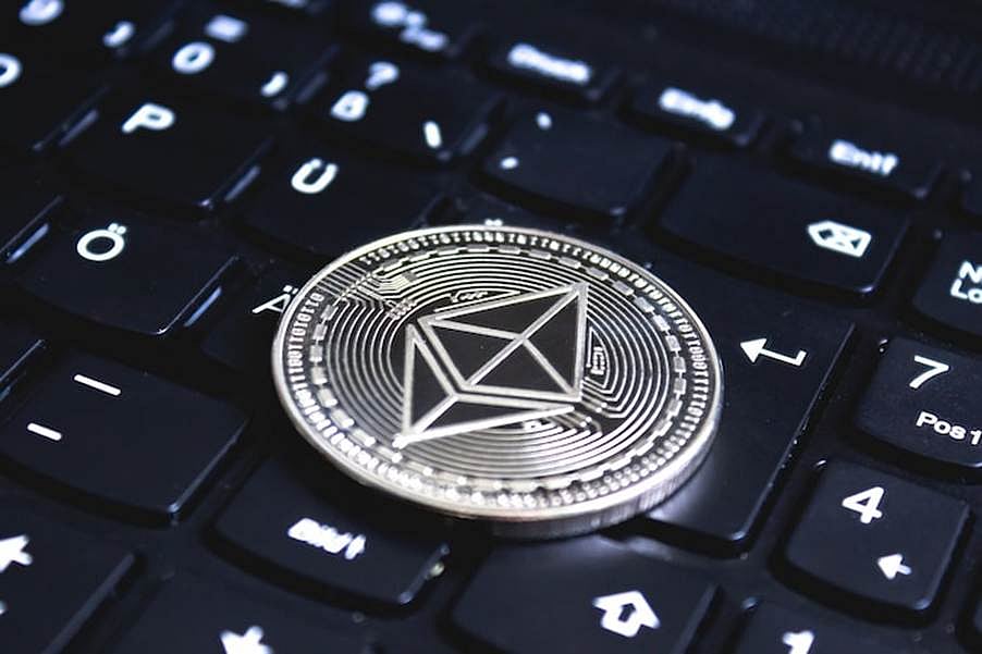 Silver Ethereum coin placed on a black computer keyboard, symbolizing digital currency
