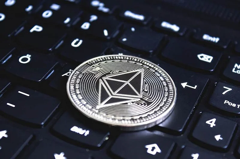 Silver Ethereum coin placed on a black computer keyboard, symbolizing digital currency