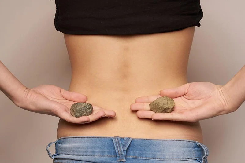 A woman holding 2 stones behind her back near her kidneys