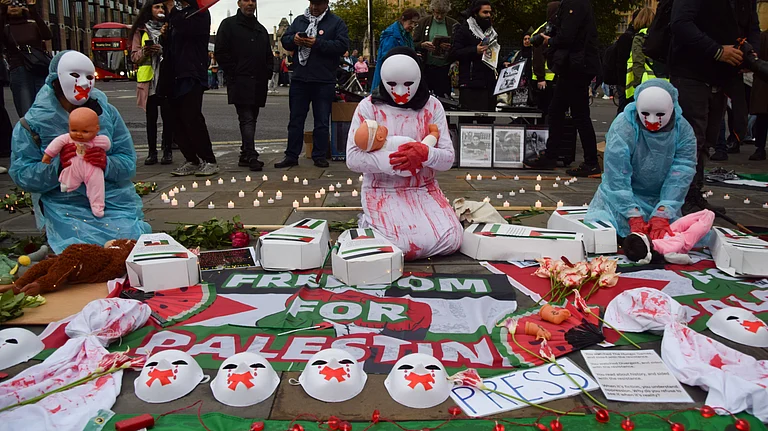 Protesters wearing masks hold dolls representing hurt and dying children as Palestine supporters stage a vigil in Parliament Square for over 41,000 people killed in Gaza on the first anniversary of the Israel-Hamas war, which began when Hamas killed and abducted Israelis at the Nova music festival on 7th October 2023. - imago |