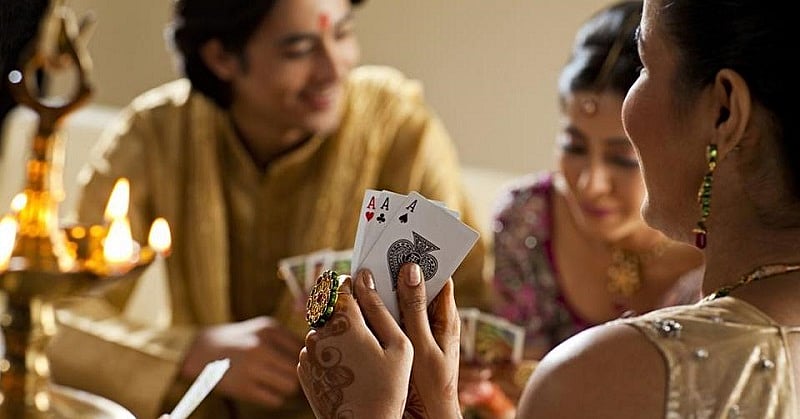 People playing card games at a Diwali house party with candles.