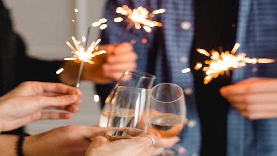 People clinking wine glasses while holding sparklers at a party or celebration.