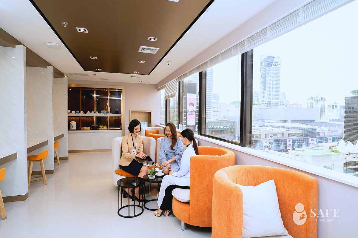 People in a modern room with orange couches and a city view