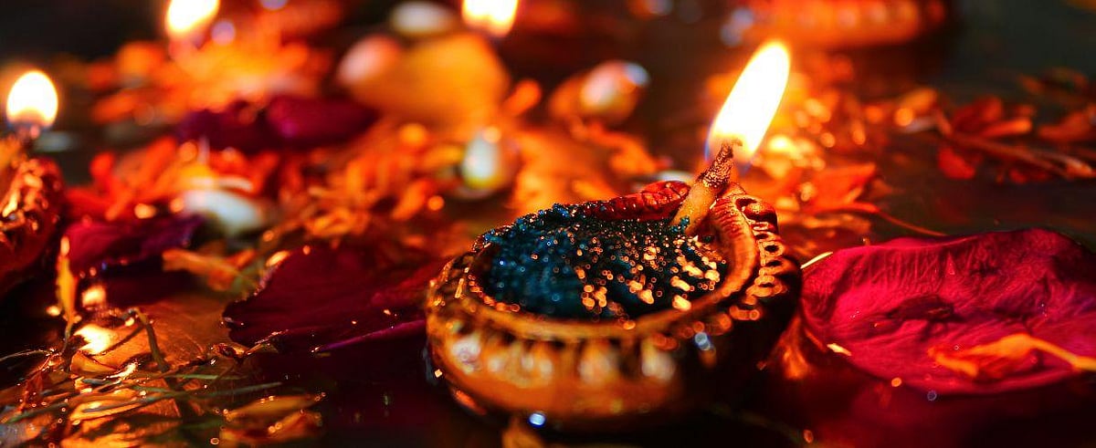 A decorated diya with a red flower, glowing festively