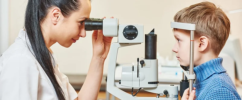 A healthcare worker conducting eye test on a child