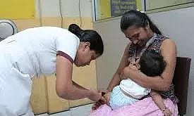 A little baby getting vaccinated while being held in its mothers arms