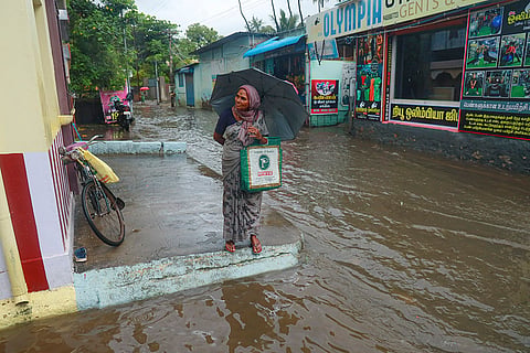 A commuter waits on an elevated section of a waterlogged road amid rain, at Nagercoil in Kanniyakumari district, Tamil Nadu.