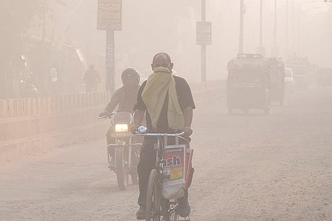 Commuters make their way amid low visibility as air quality deteriorates across Northern India, in Gurugram, Haryana.