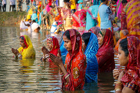 People offer prayers to the sun while standing in a lake during Chhath Puja festival, in Agartala.