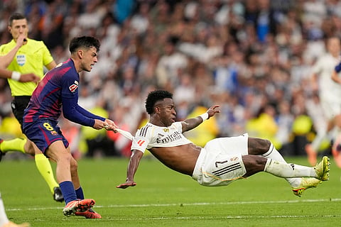 Barcelona's Pedri pulls Real Madrid's Vinicius Junior during a La Liga soccer match between Real Madrid and Barcelona in Madrid, Spain.