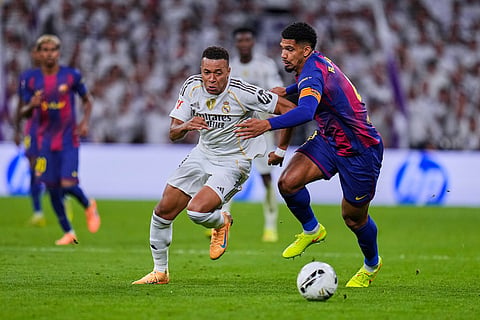 Real Madrid's Kylian Mbappe, left, fights for the ball with Barcelona's Ronald Araujo during the Spanish La Liga soccer match between Real Madrid and Barcelona, in Madrid.
